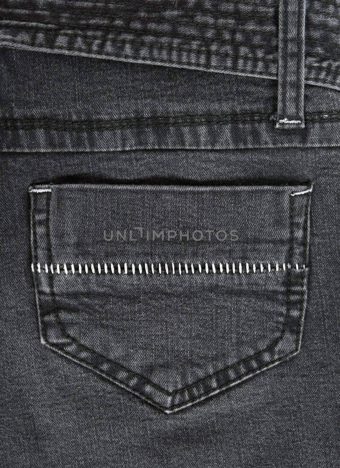 Closeup of black jeans pocket with white stitches.