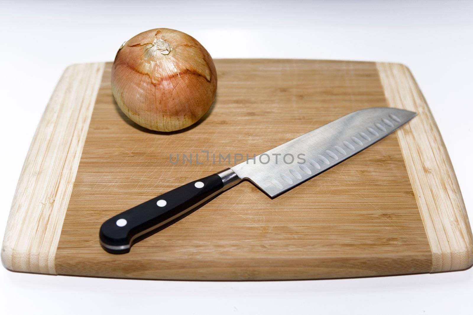 Onion and Knife sitting on a Cutting Board with a white background.
