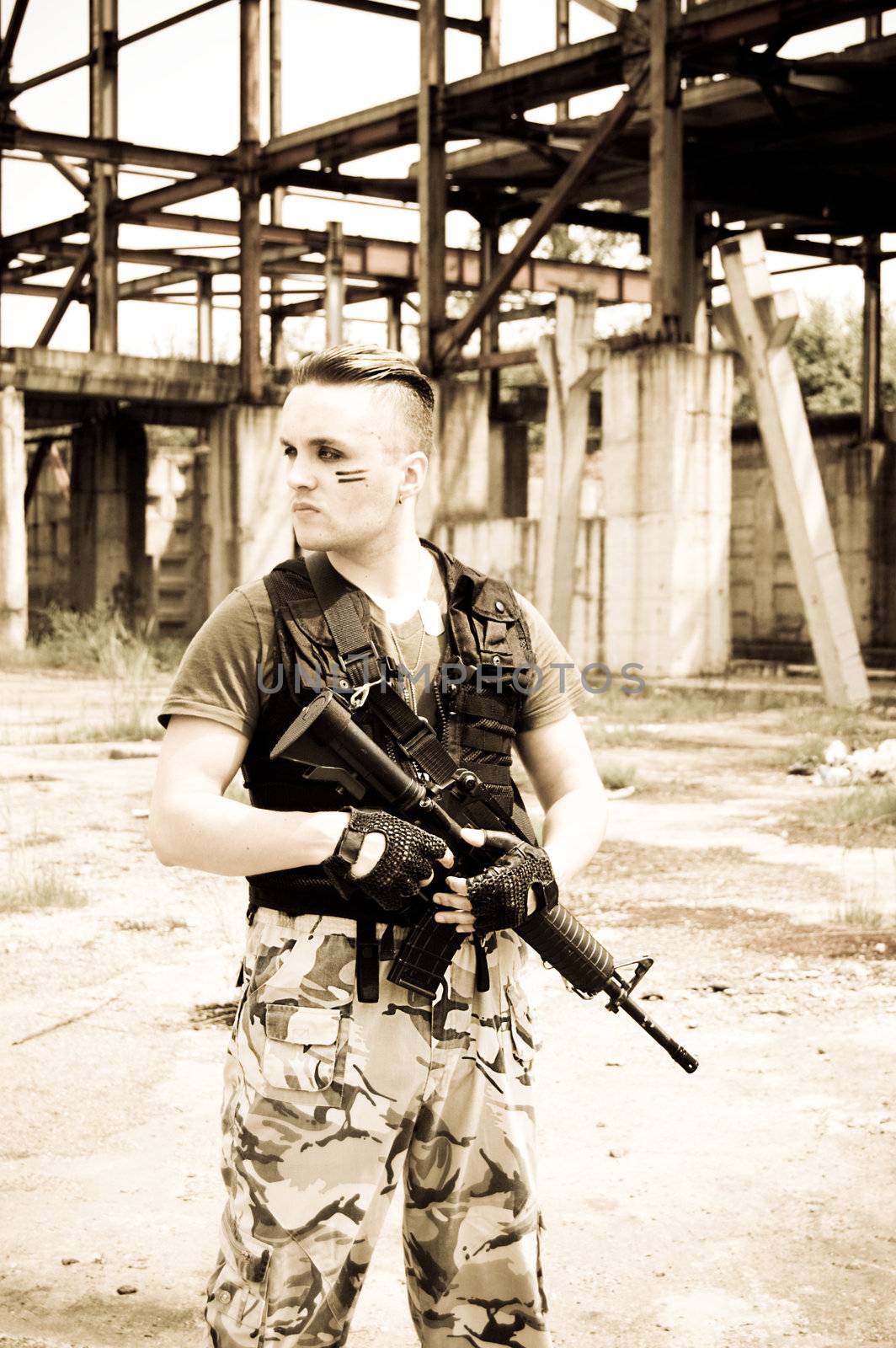 Man in camouflage with gun over metallic construction