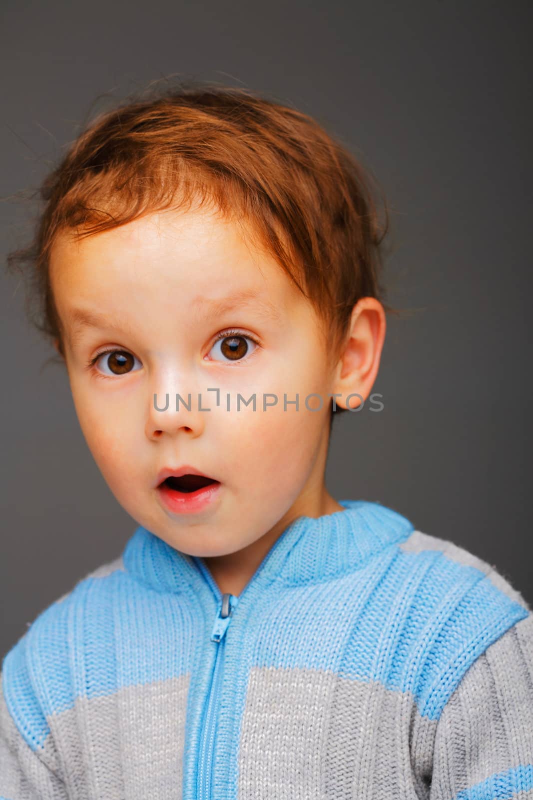 Closeup portrait of a little surprised boy in a blue sweater