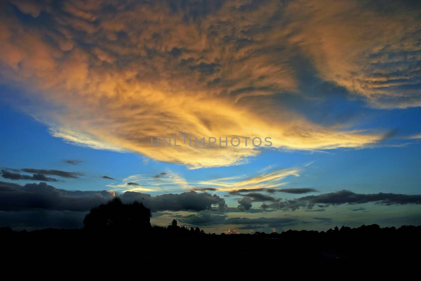 A beautiful orange sunset with blue sky, fluffy clouds.