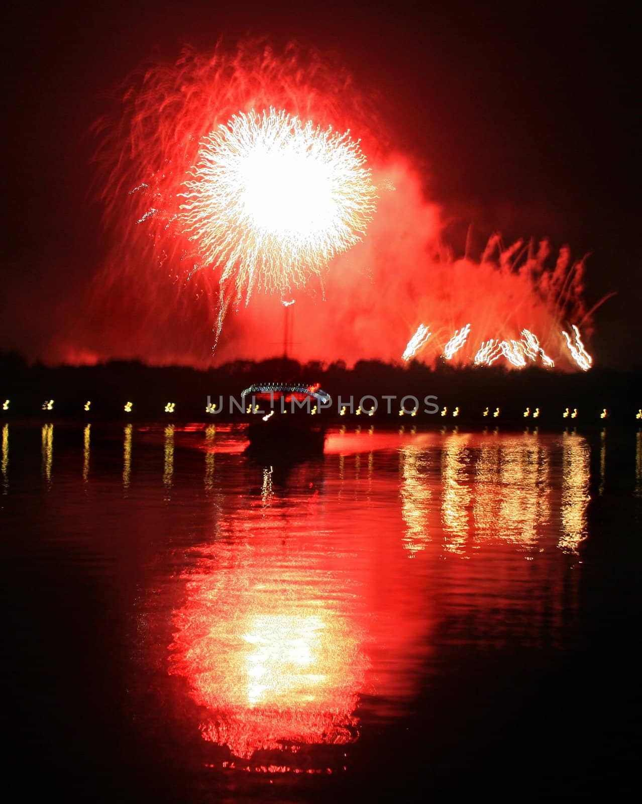 Fireworks with reflections in a lake and a boat.