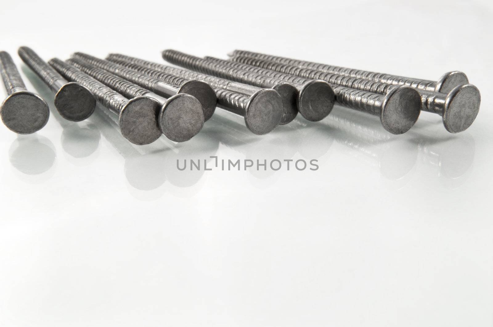 Close and low level angle of a group of steel nails arranged on white.