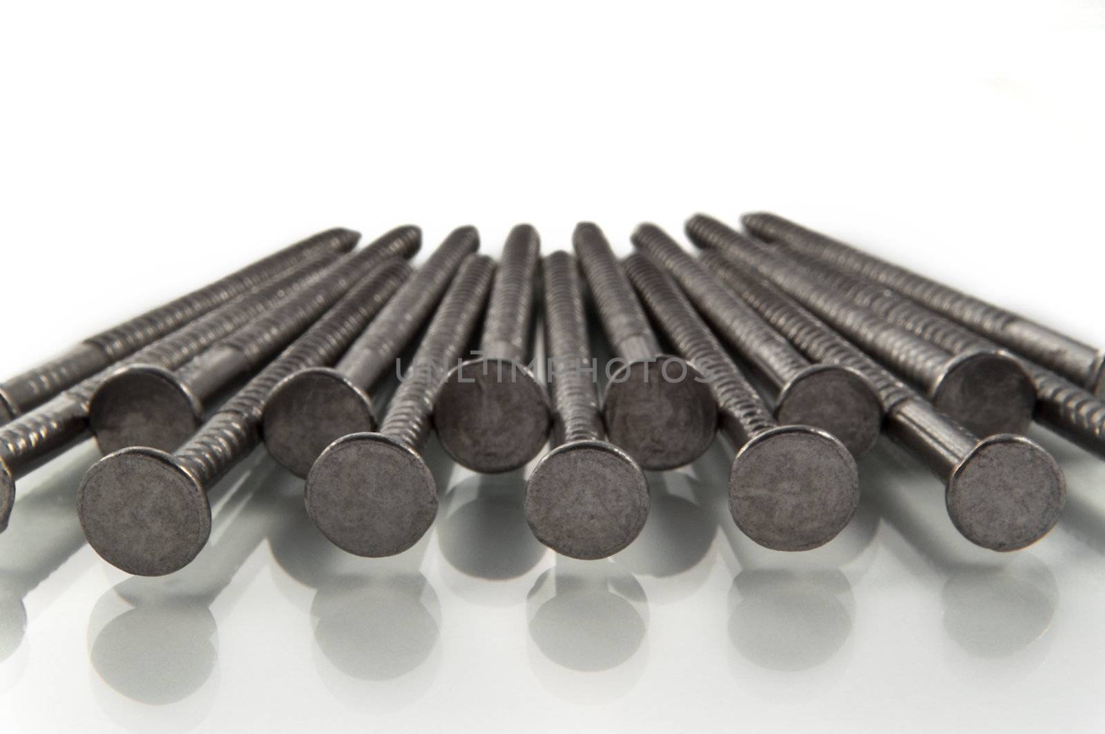 Close and low level of the heads of a number of steel nails arranged in a repetitive pattern.
