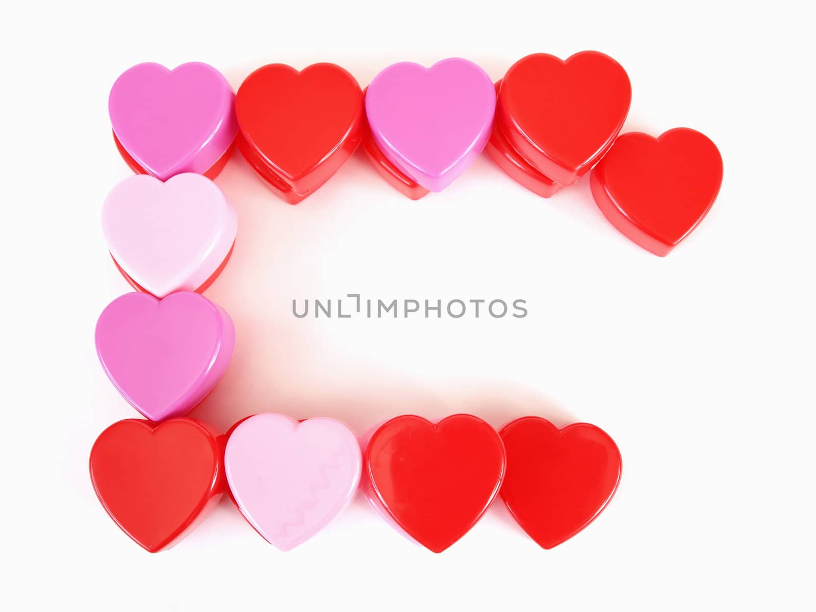 Assorted heart shapes in red, pink and purple arranged with room for text against a white background.