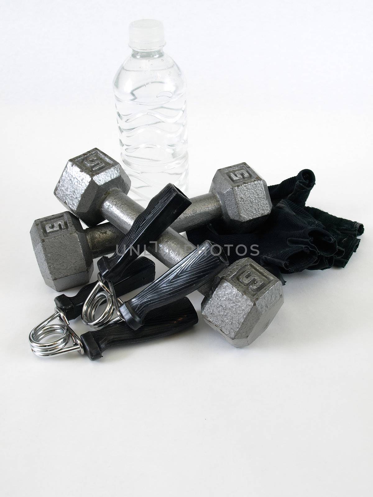 Five pound handweights, grip trainers, gloves and a water bottle, over a white background.