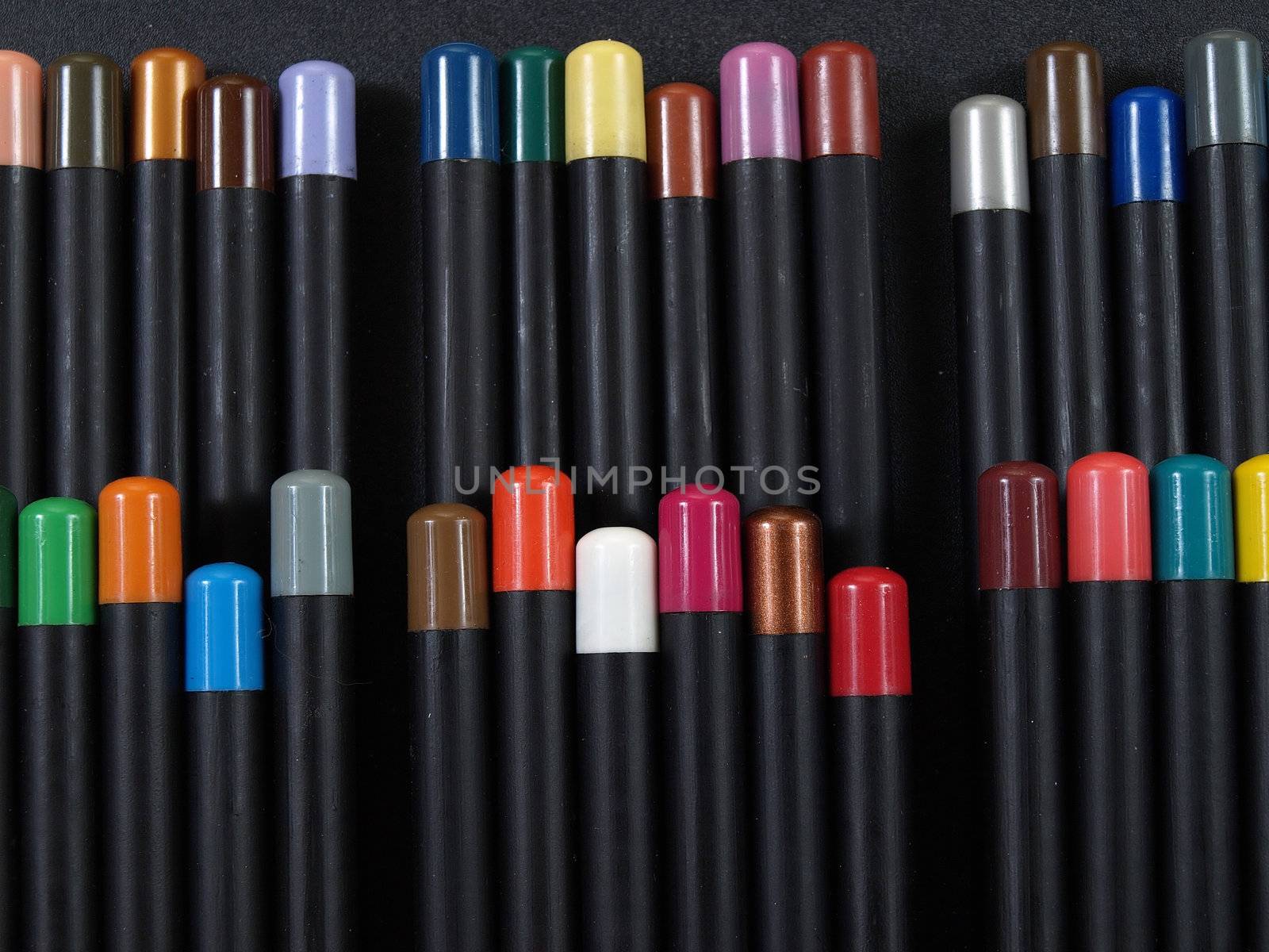 Artist pencils with identifying colored tops arranged against a black background.