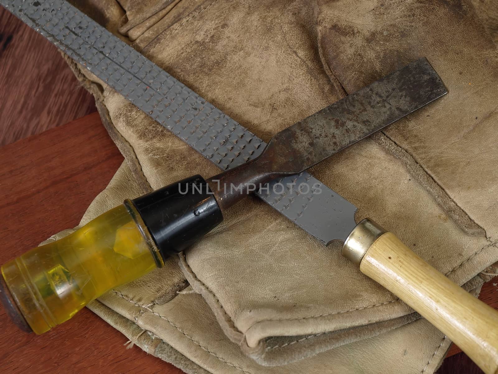 An old chisel and a rasp with a pair of leather work gloves.