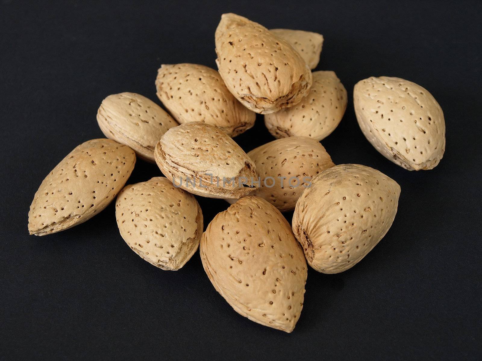 A small group of almonds isolated against a black background.