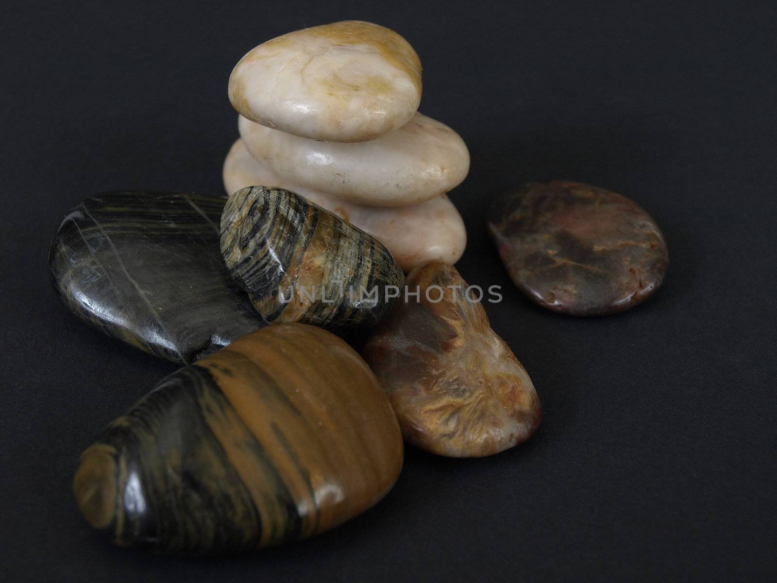 Smooth polished stones stacked and single against a black background.