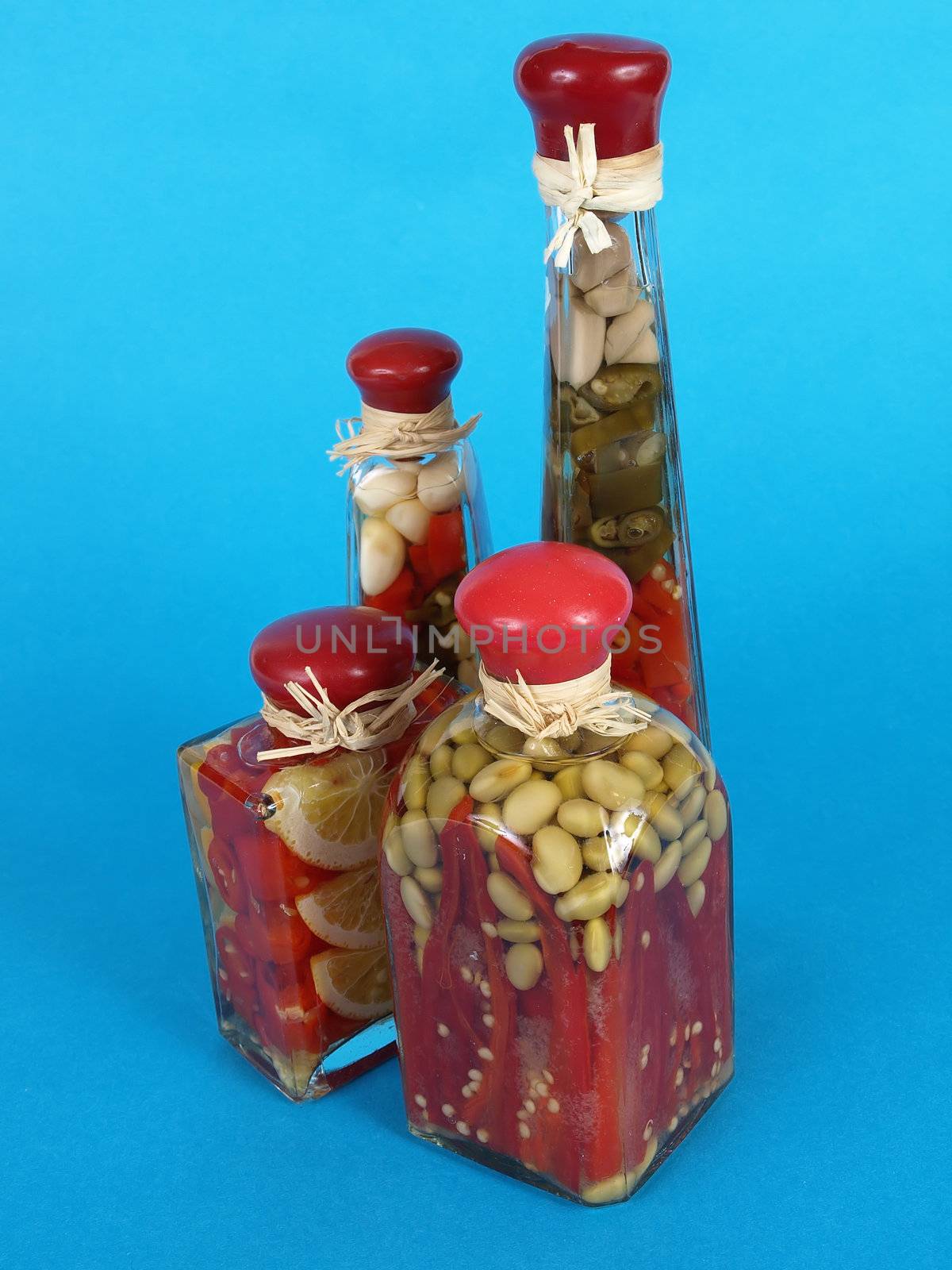 A colorful assortment of pickled spices in different shaped jars over a blue background.