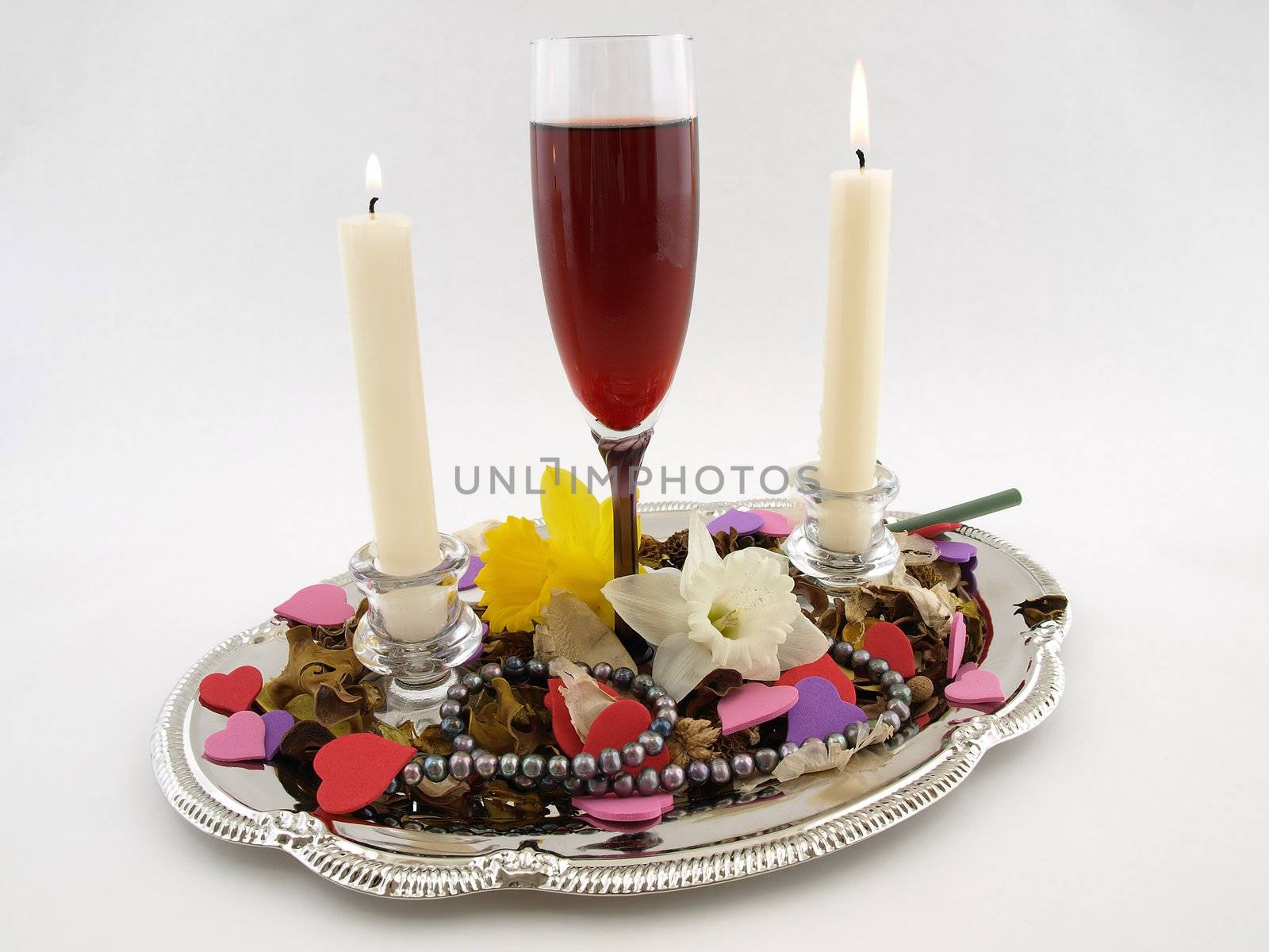 Silver tray with candles, red wine, flowers and pearls isolated on a white background