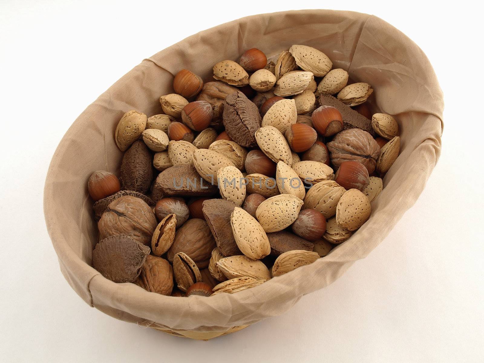 Various nuts in a cloth covered basket. Over a white background.