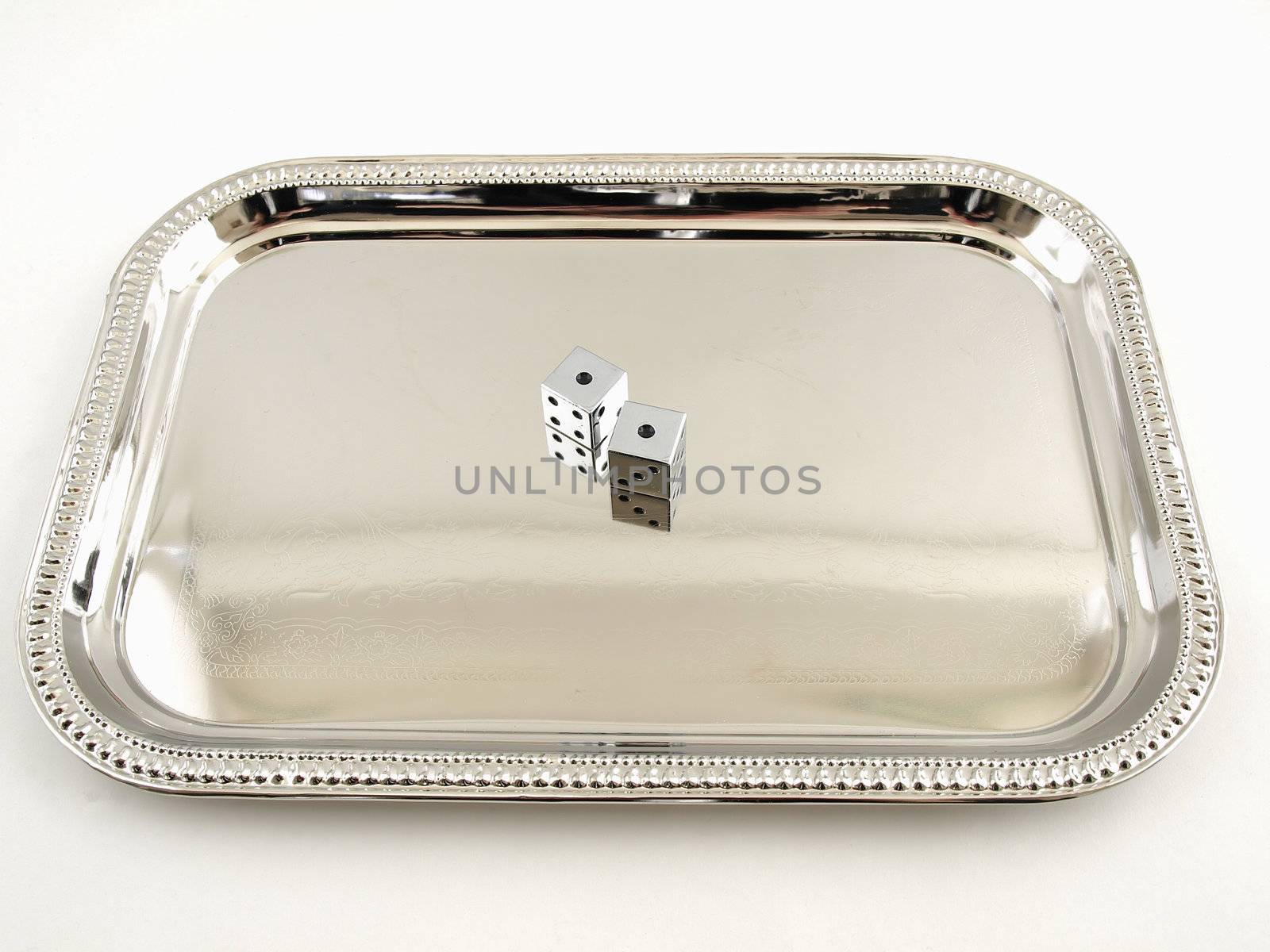 Two silver dice sitting on a Silver tray isolated on a white background