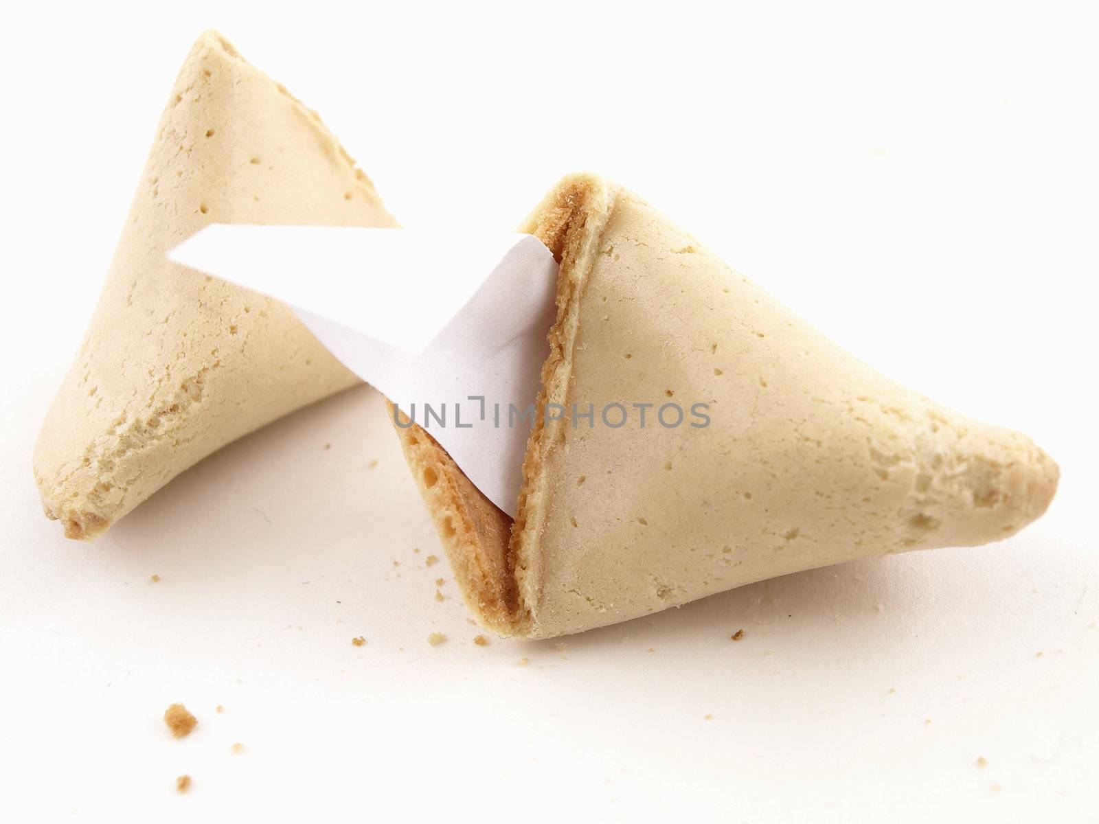 A broken fortune cookie over a white background. Cookie has blank fortune sticking out of one side.