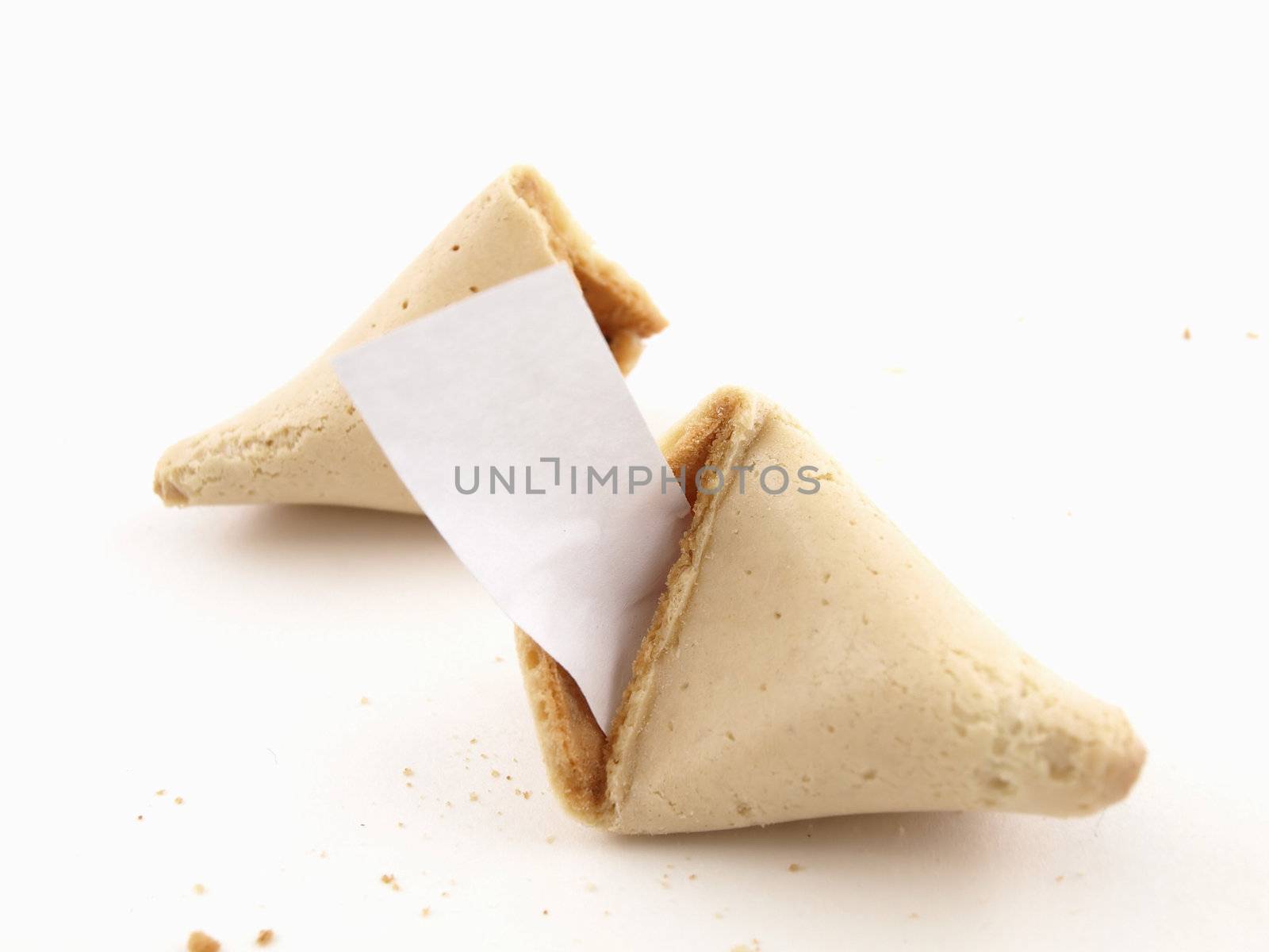 A broken fortune cookie over a white background. Cookie has blank fortune sticking out of one side.