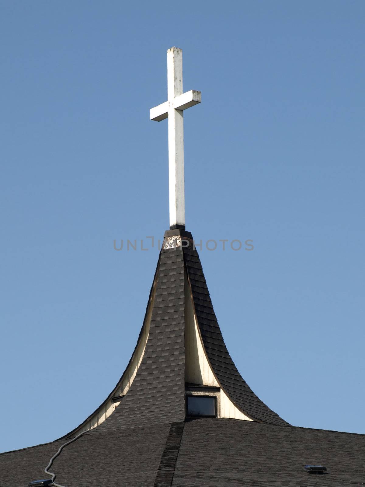 A white wooden cross atop a church steeple.
