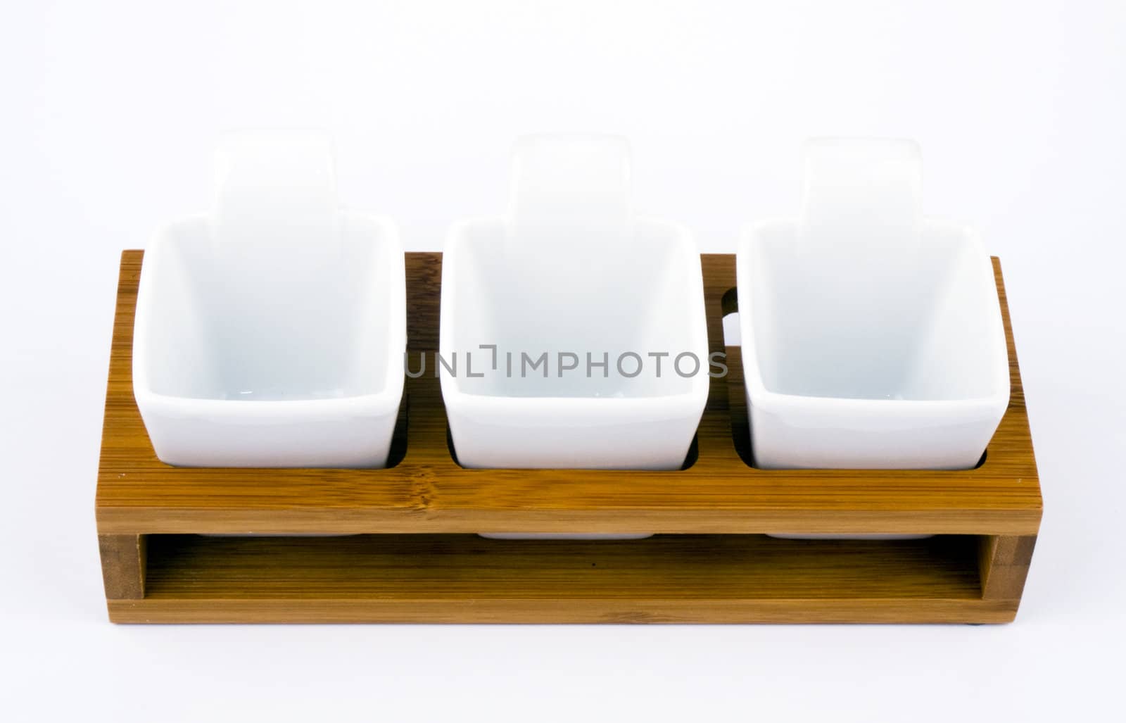 Three white porceline bowls placed on wooden support.