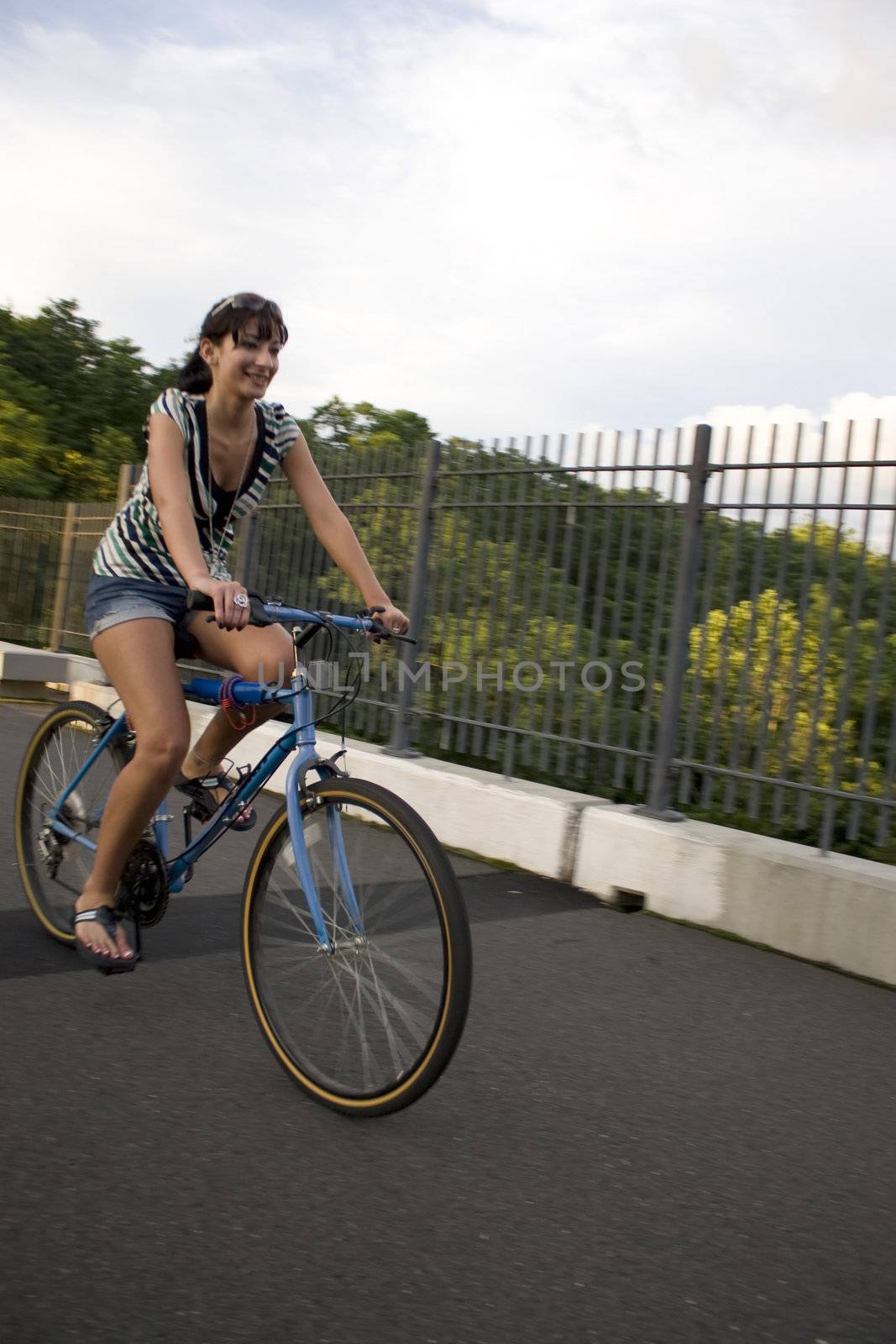 A young woman riding a bicycle across the bridge.