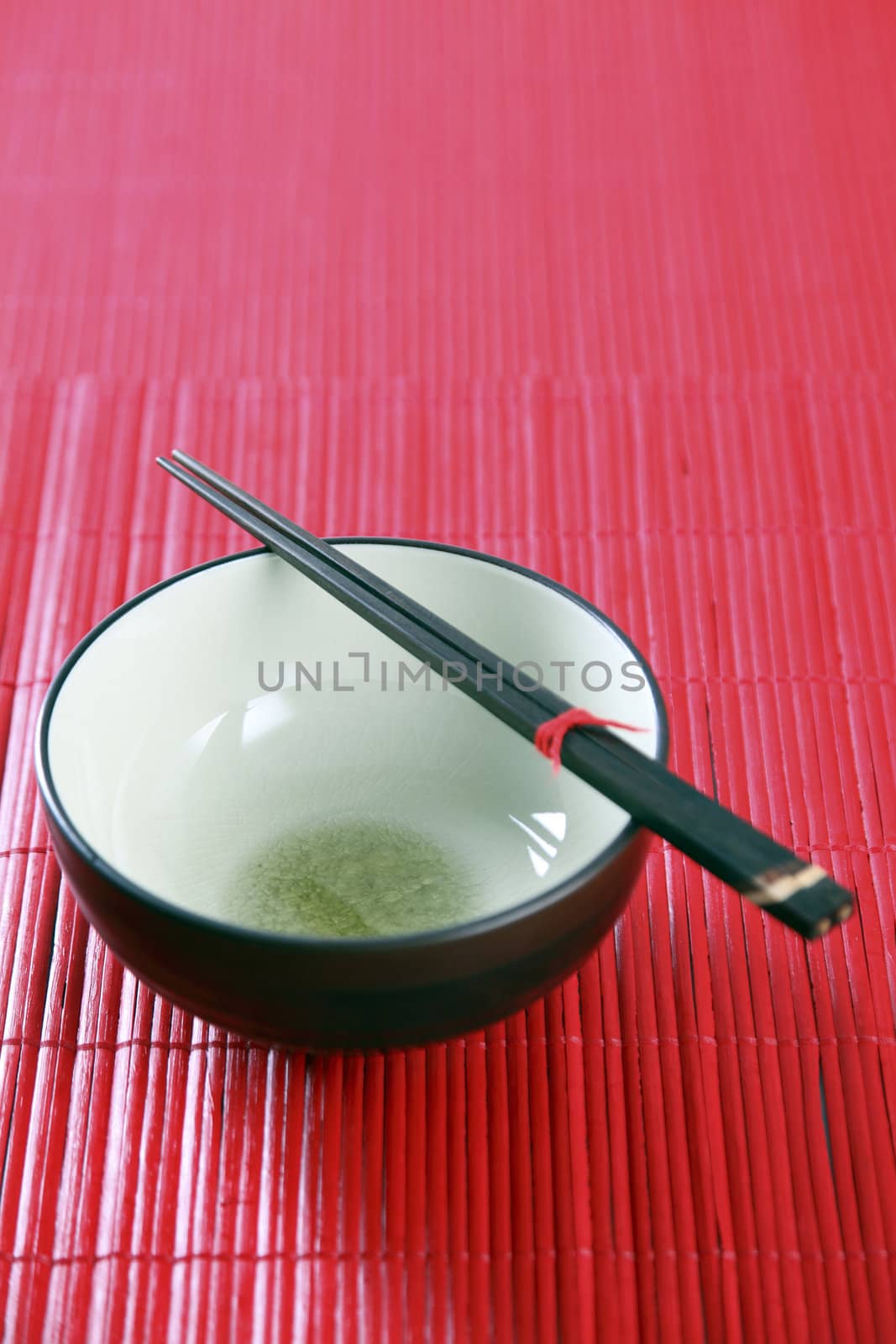 Asian bowl and chopsticks on the red background