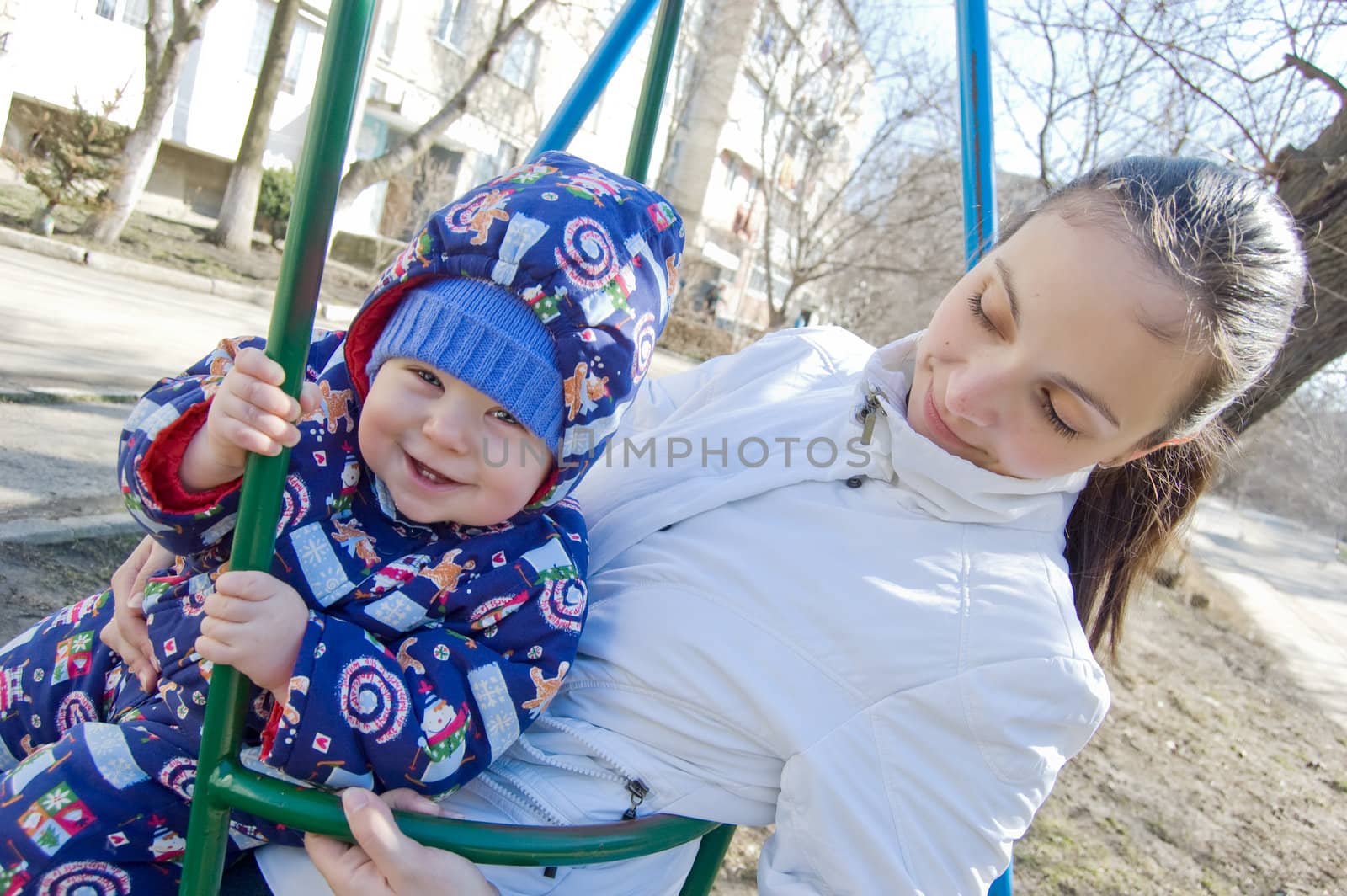Happy baby boy and his mother on swing