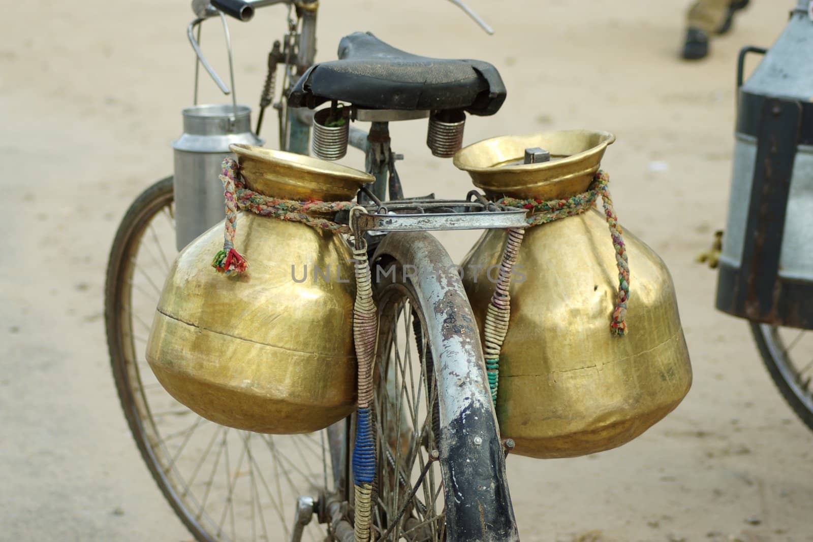 Two large copper milkpots tied to aa old bicycle, Ajmer, India.