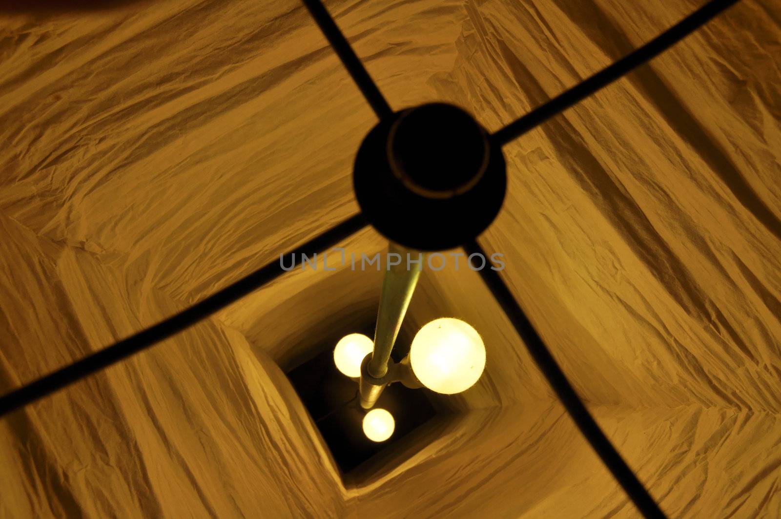 View from above into a paper lamp with 3 burning lightbulbs