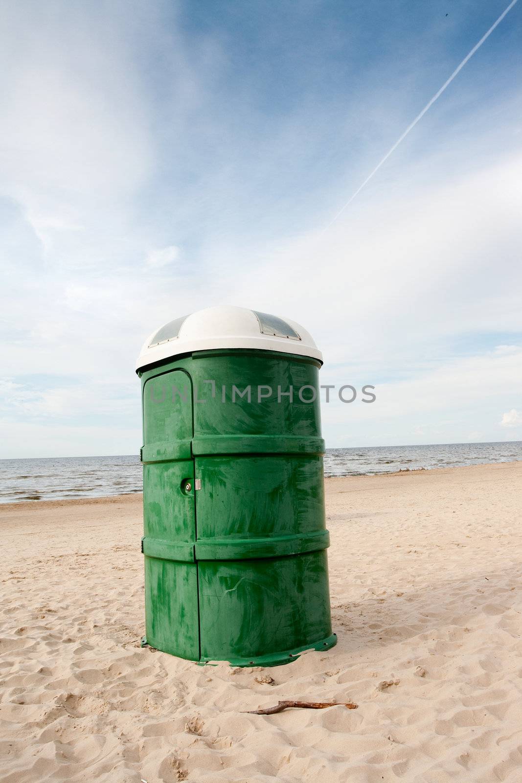 Green plastic portable toilet in the sandy beach