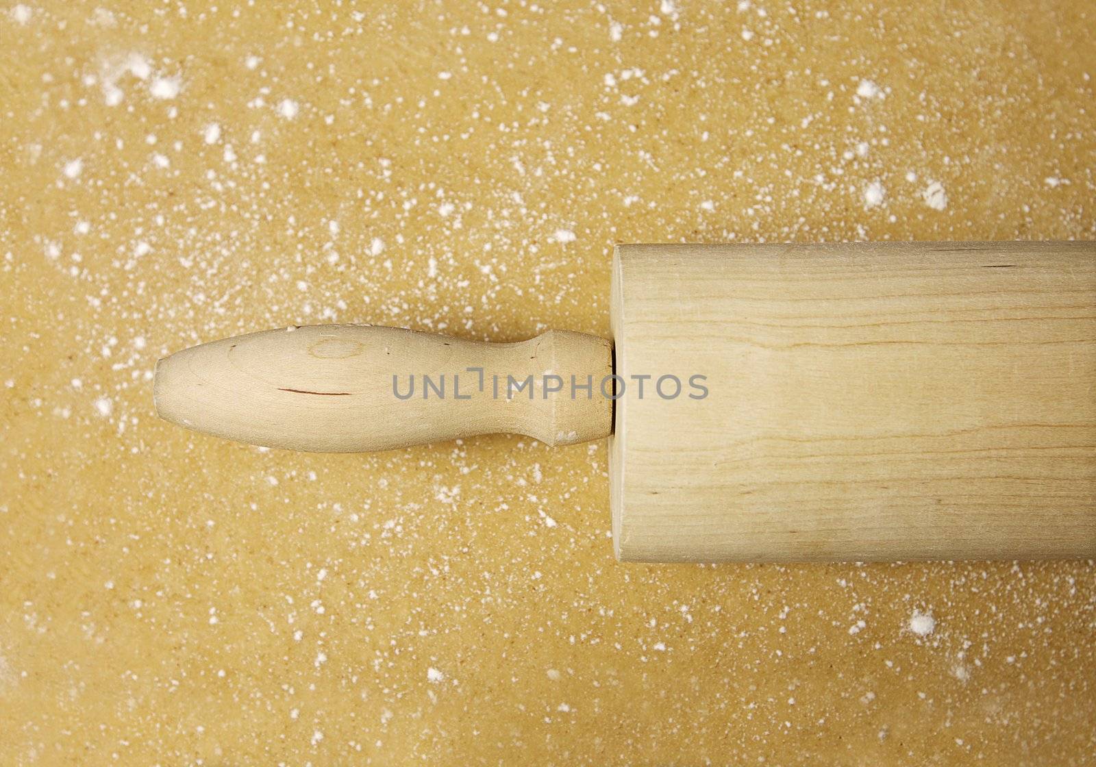 Close-up of a wooden rolling pin on flattened dough