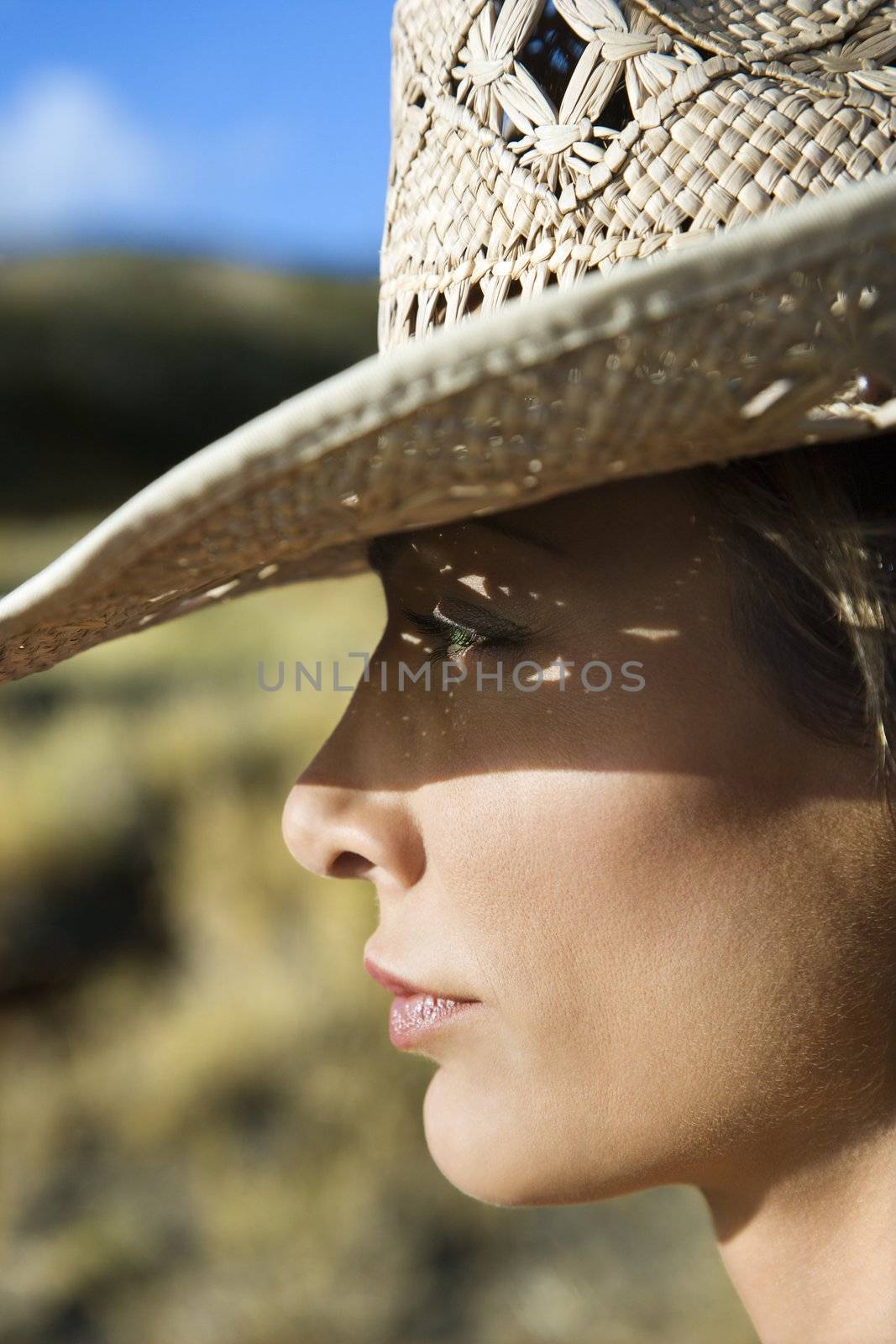 Close-up profile of mid-adult Caucasian woman wearing straw cowboy hat.