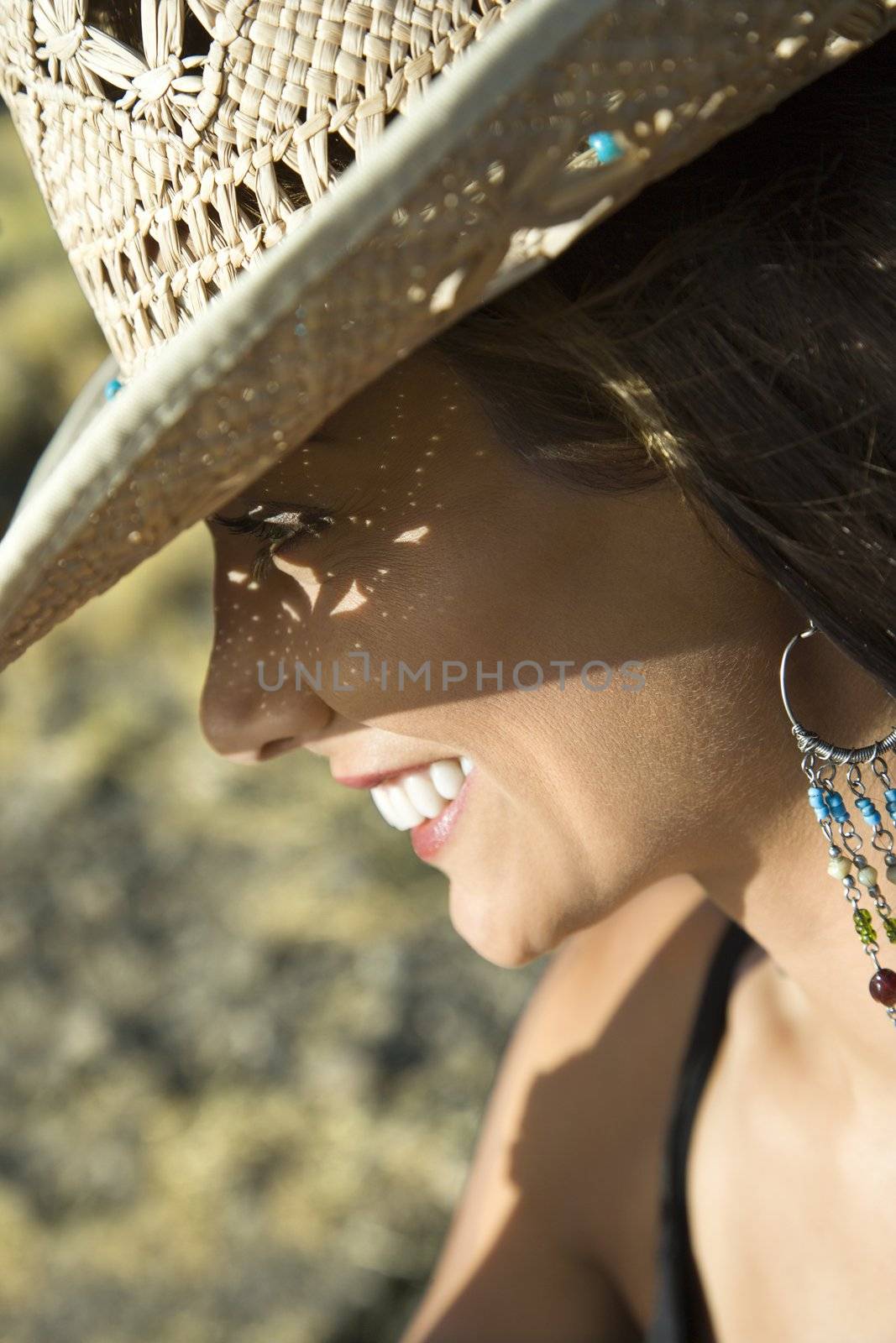 Close-up profile of smiling young mid-adult Caucasian woman wearing straw cowboy hat.