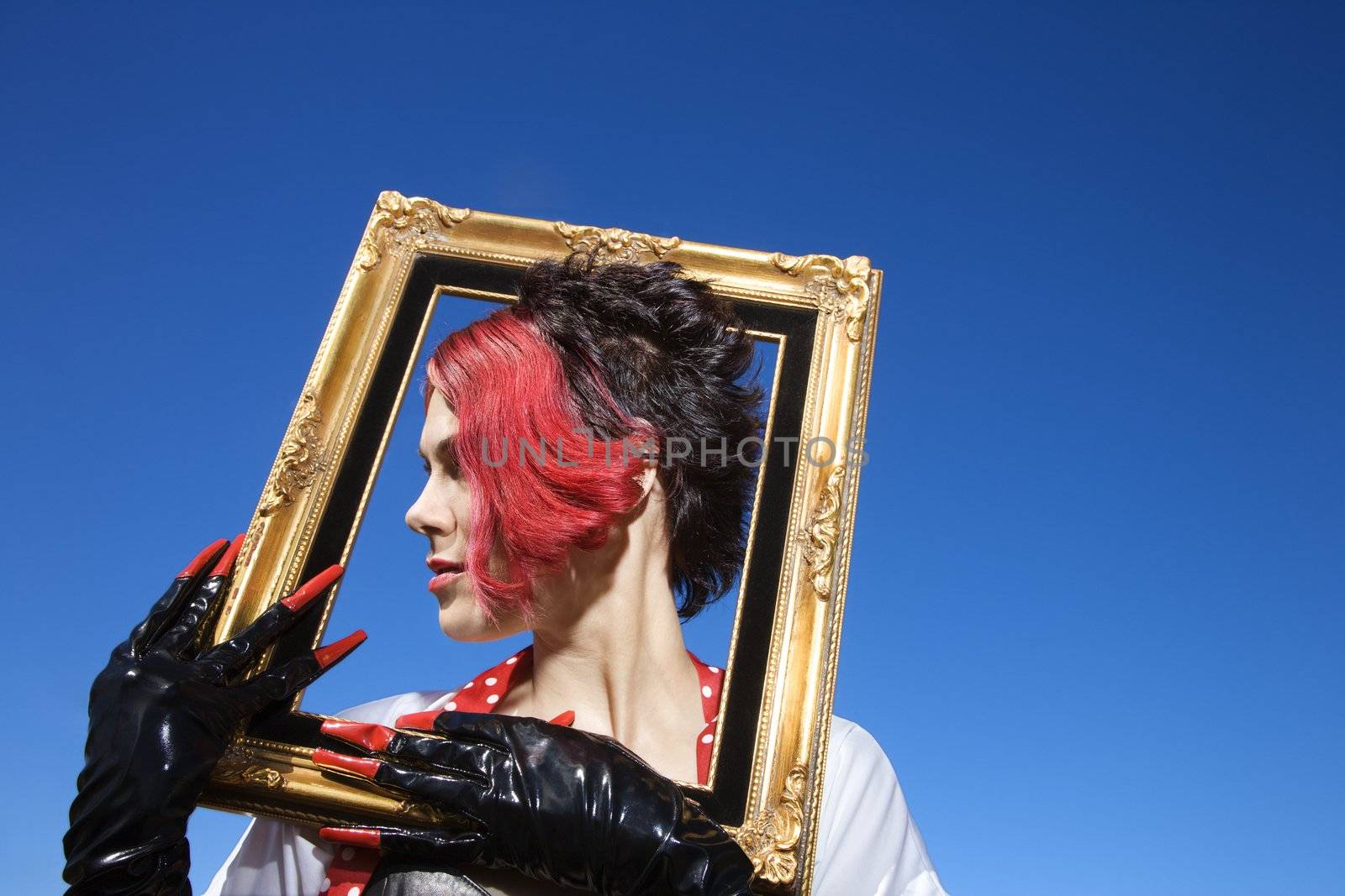 Young adult Caucasian female holding empty frame around head.