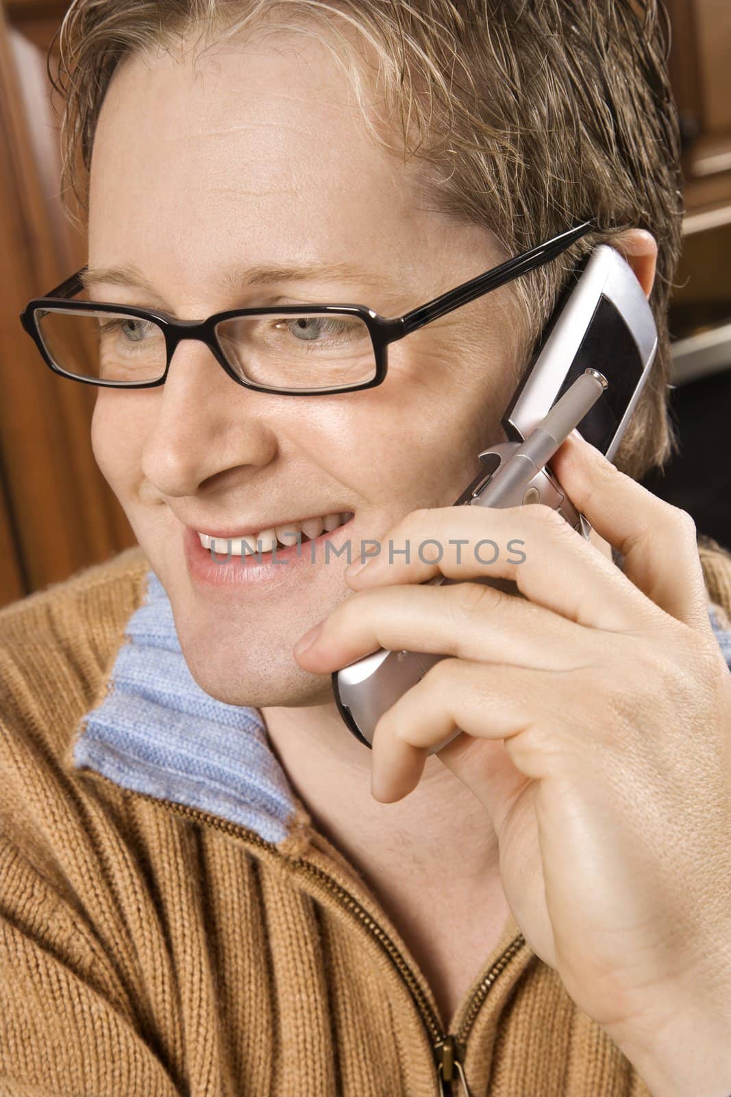 Caucasian man smiling and talking on cellphone.