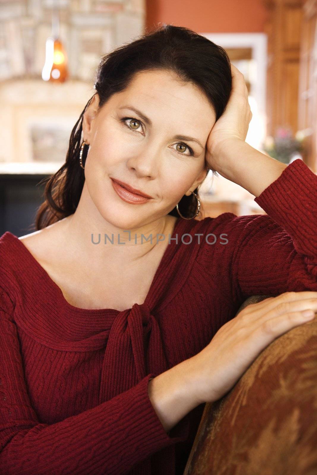 Brunette Caucasian woman with head resting on hand looking at viewer.