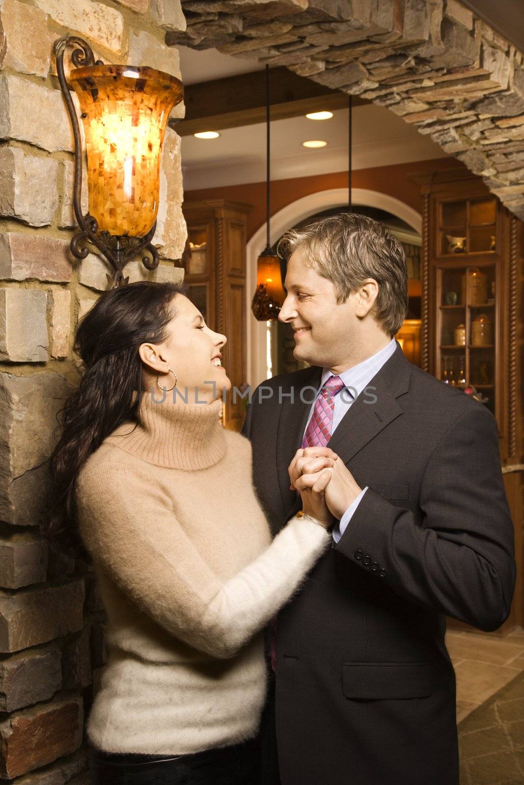 Caucasian woman and Caucasian man holding hands looking at each other and smiling.