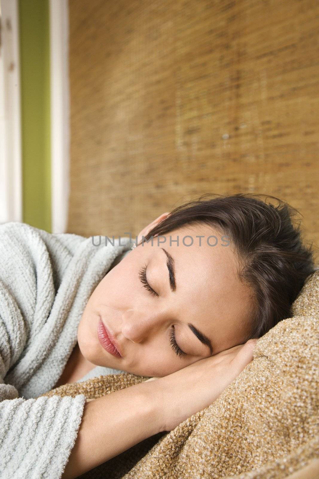 Caucasian/Hispanic young woman with eyes closed laying down.