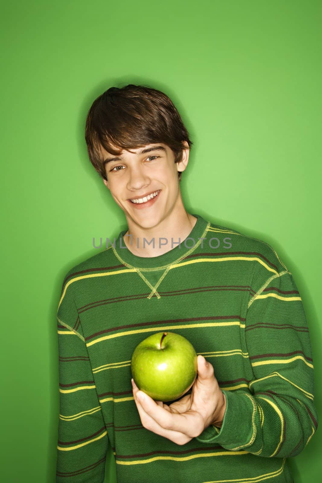 Portait of Caucasian teen boy holding apple.