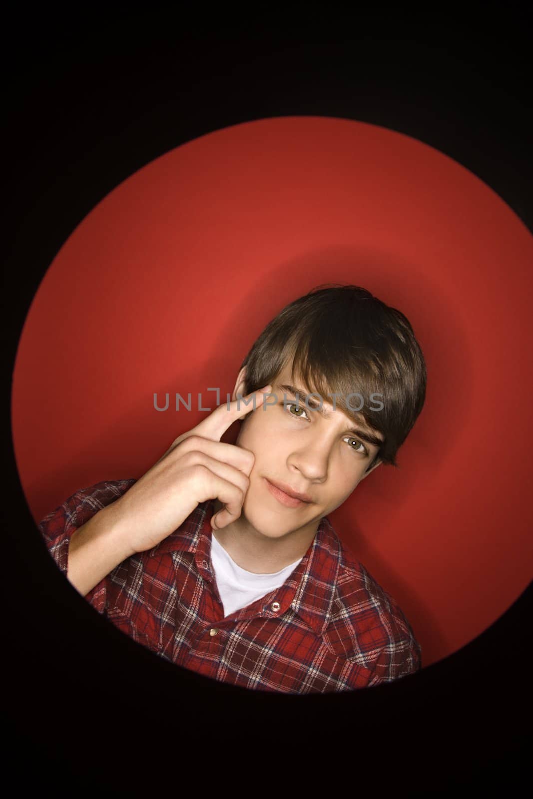 Portrait of Caucasian teen boy pointing to his head.