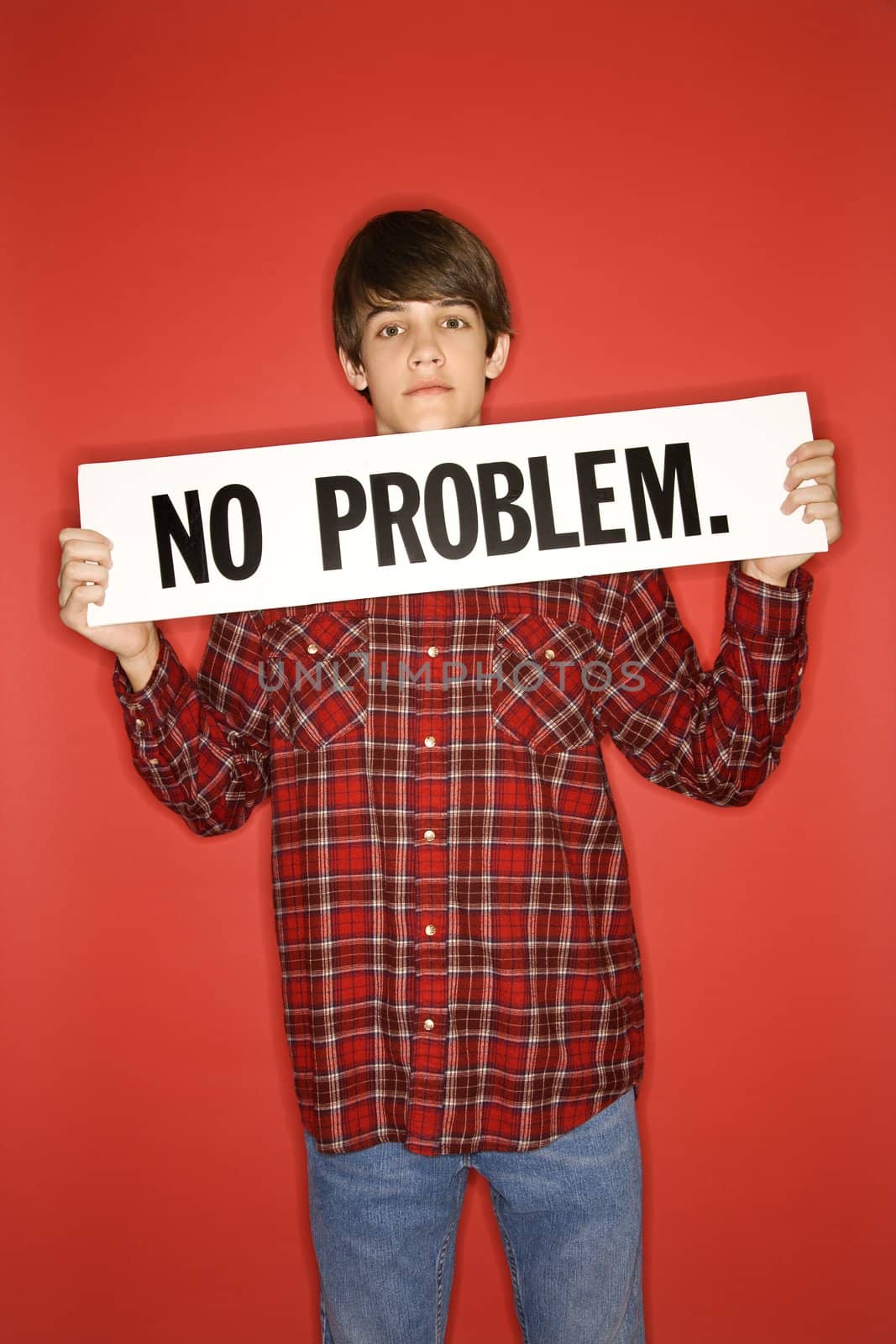 Portrait of Caucasian teen boy holding no problem sign under his chin.