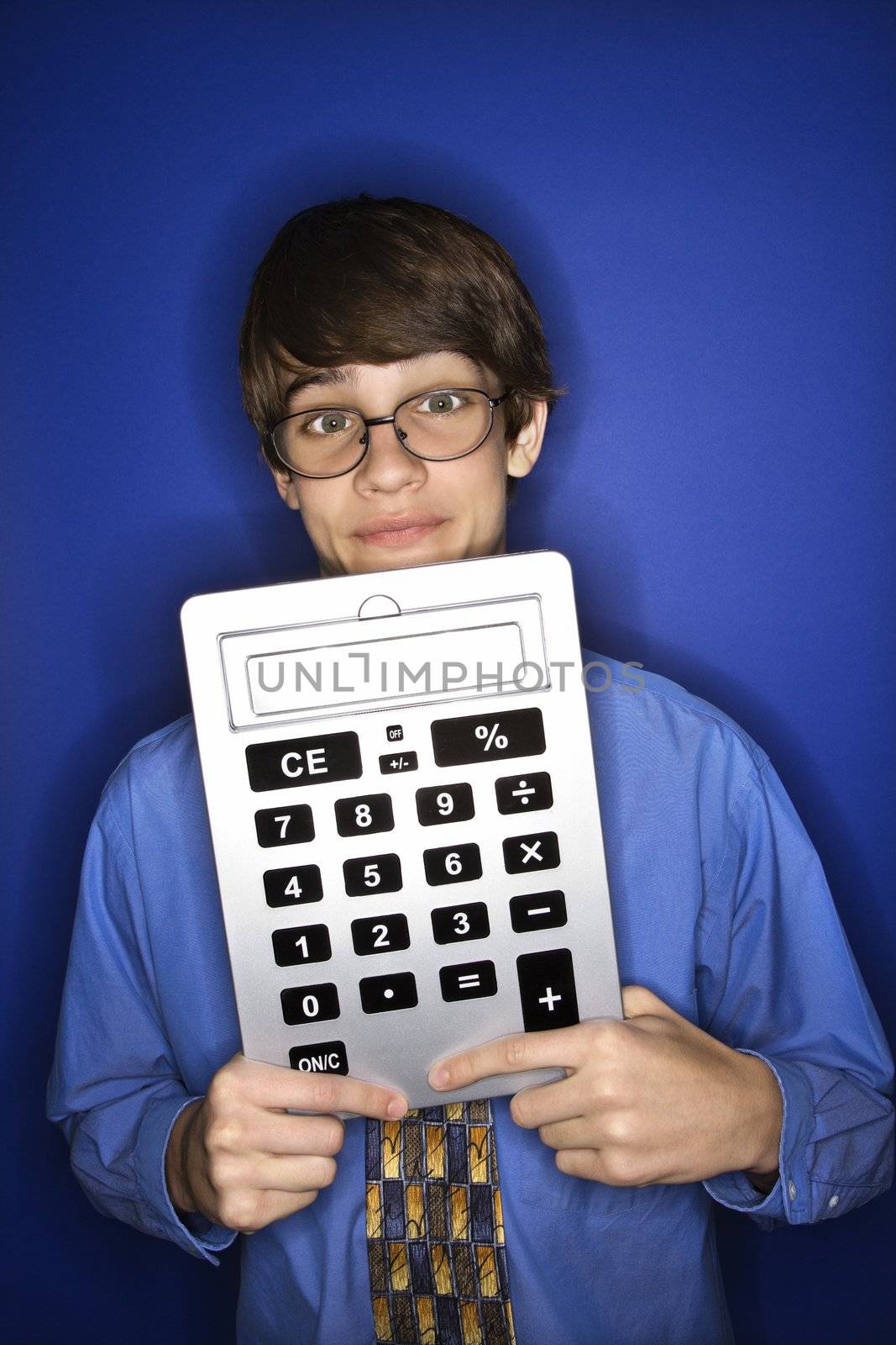 Portrait of Caucasian teen boy wearing eyeglasses and necktie holding oversized calculator.