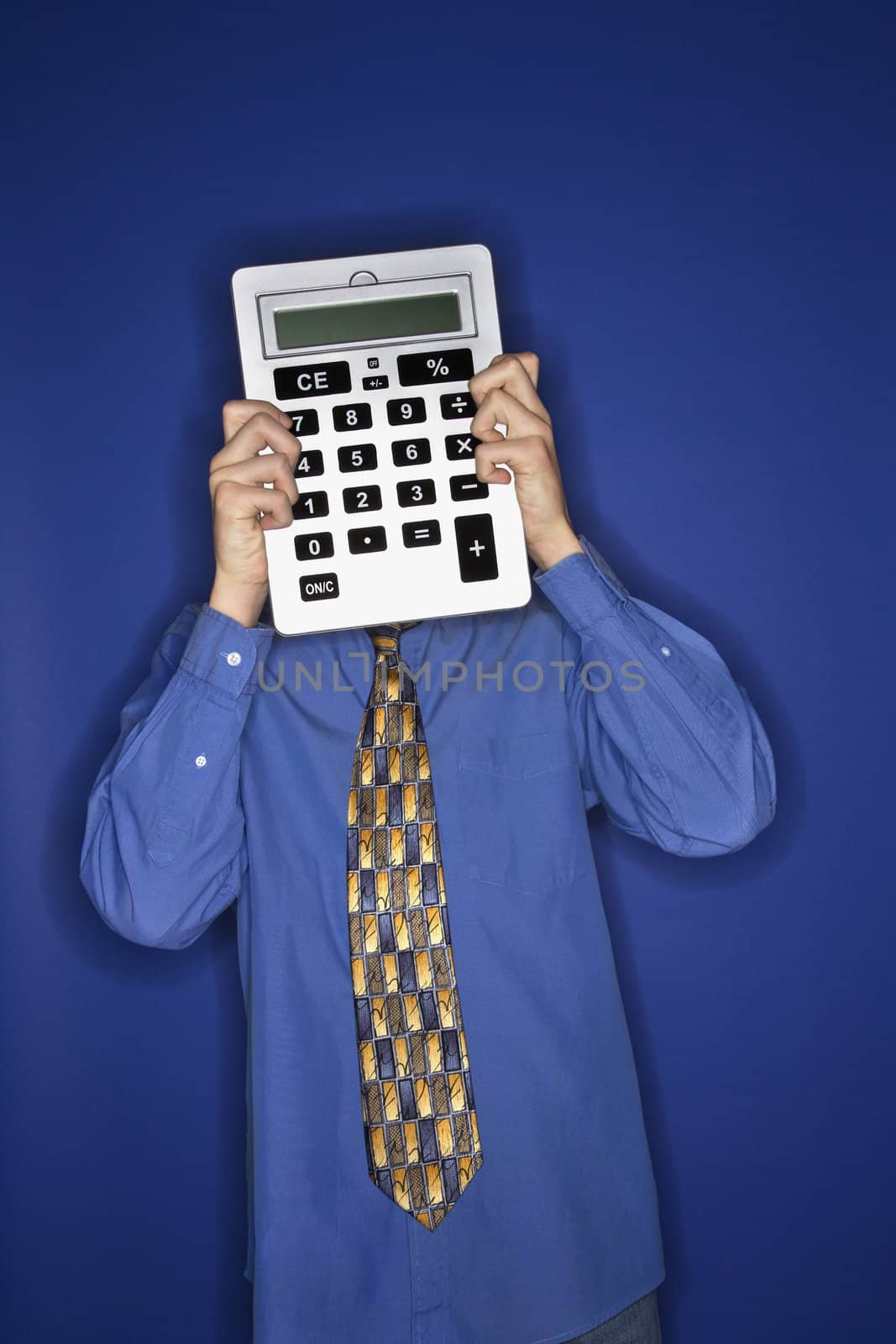 Portrait of Caucasian teen boy holding big calculator in front of face.