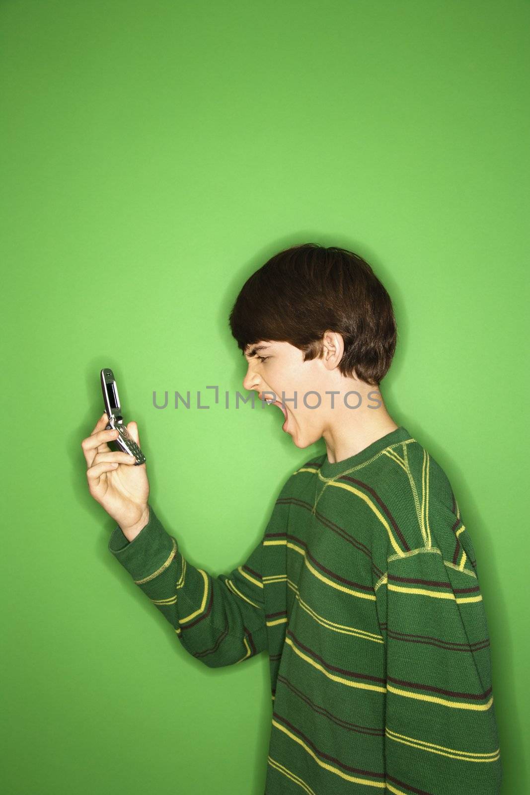 Portrait of Caucasian teen boy screaming at cellphone.