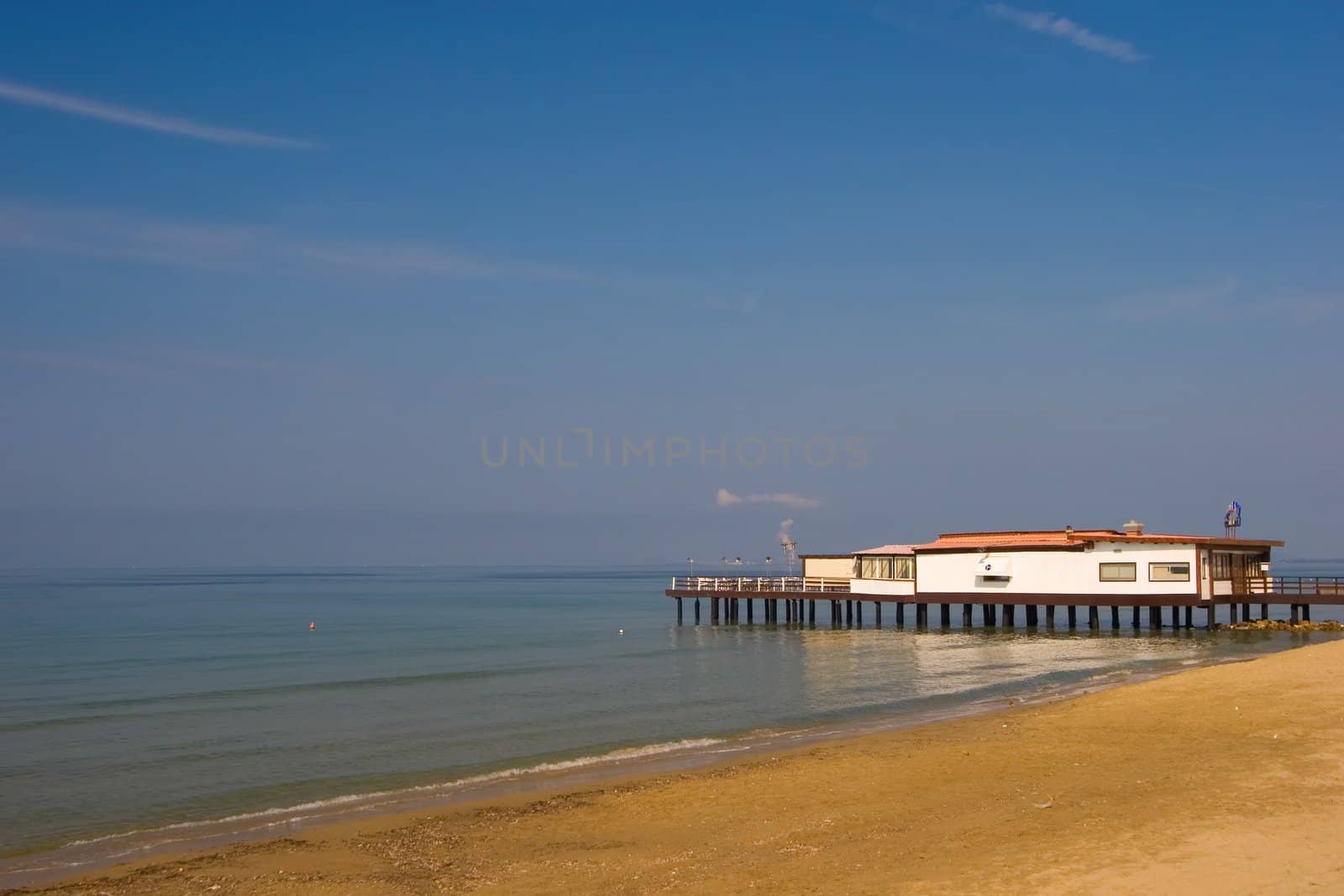 A view over the mediterranean sea, with a white house on an Italian beach