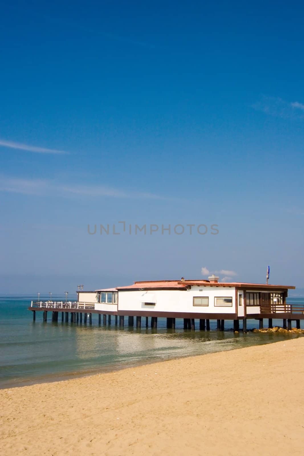 A view over the mediterranean sea, with a white house on an Italian beach