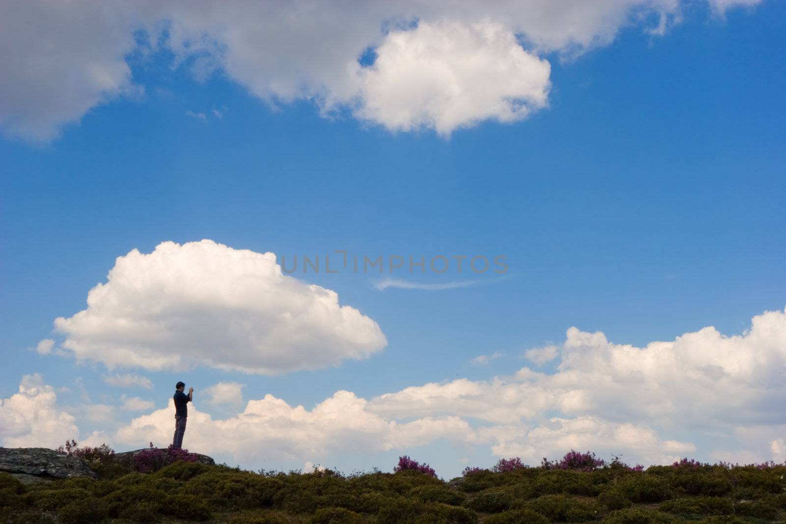 Man meditating outdoors. Beautiful sky with fluffy white clouds