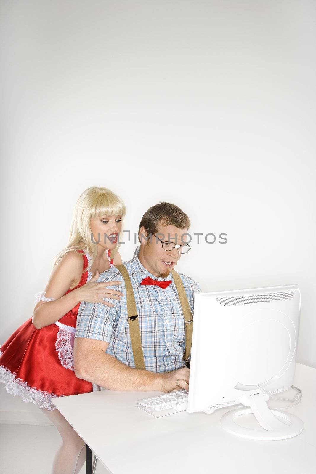 Caucasian young man dressed like nerd with Caucasian young blonde woman dressed in french maid outfit looking over shoulder.