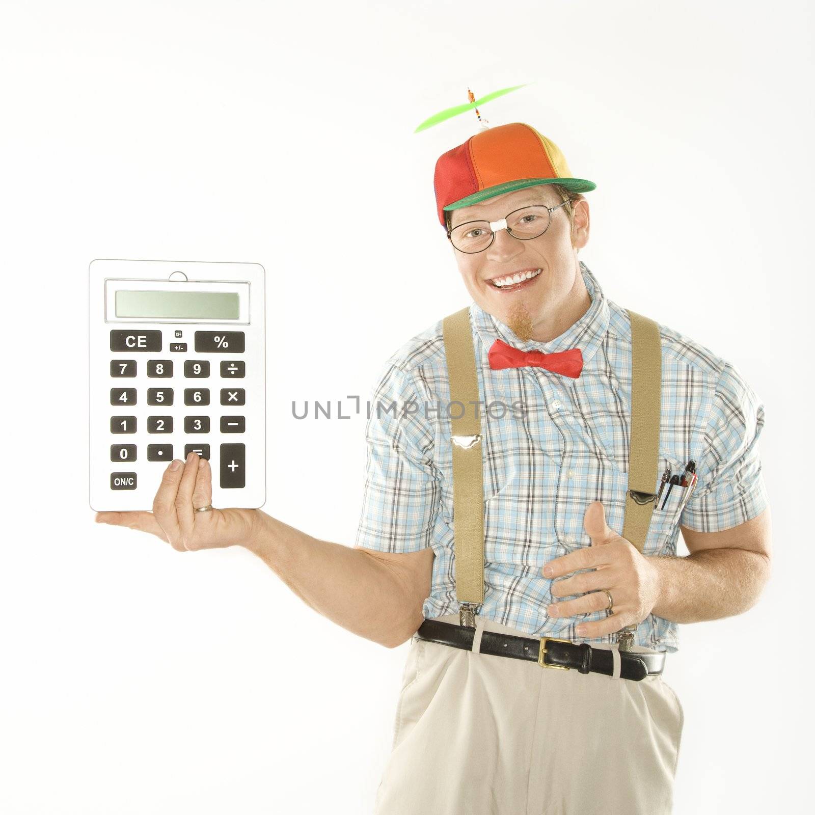 Caucasian young man dressed like nerd wearing beanie holding large calculator.