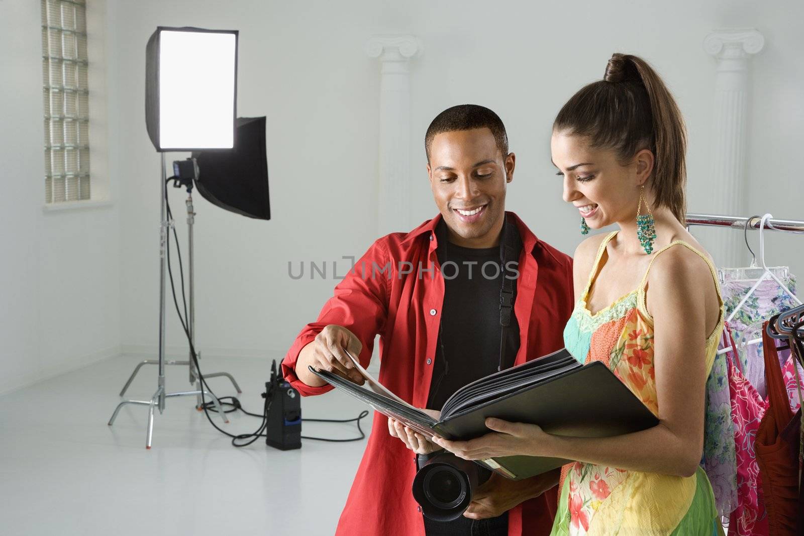 African American young male adult photographer and young adult female model looking at portfolio.