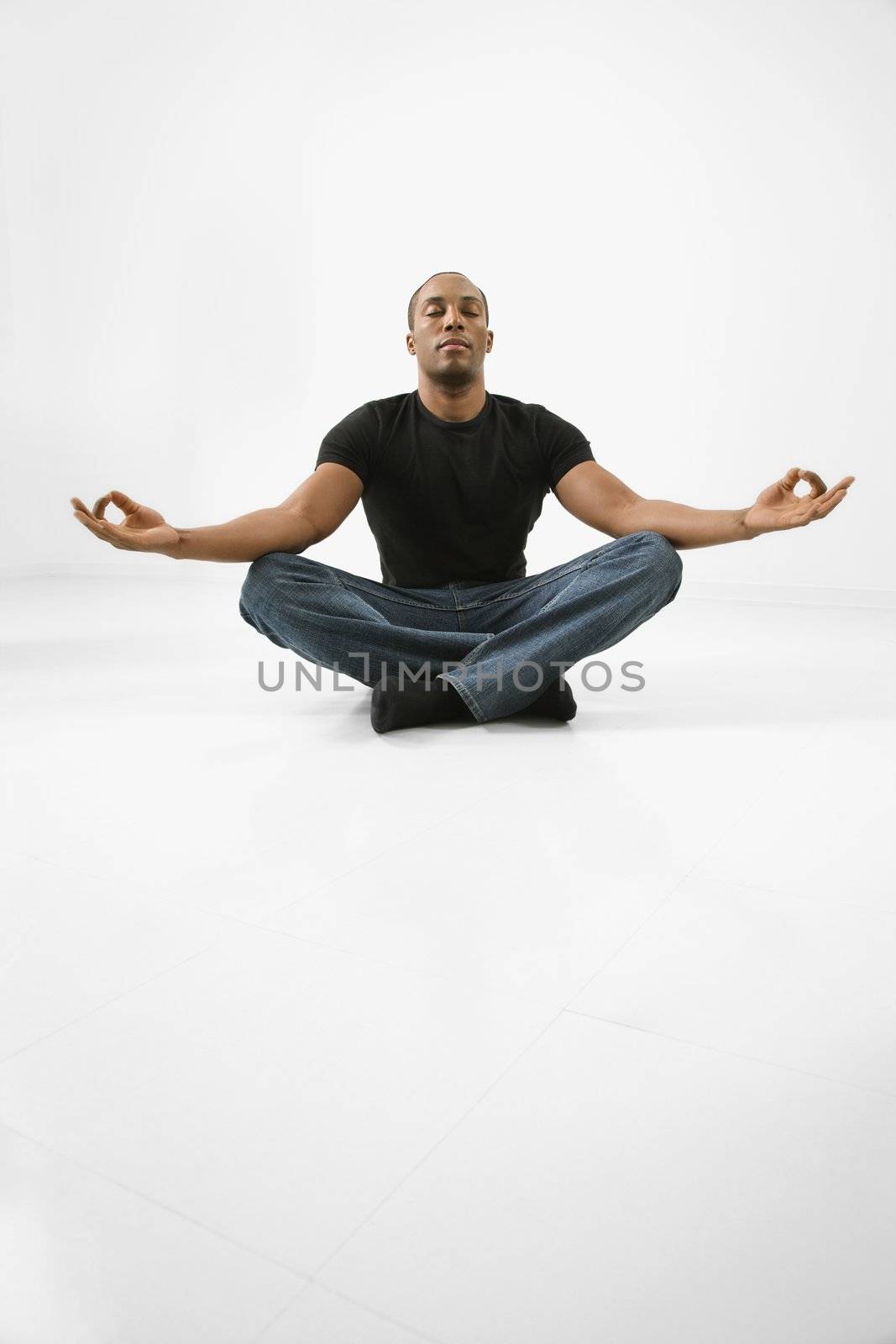 African American young male adult sitting meditating.
