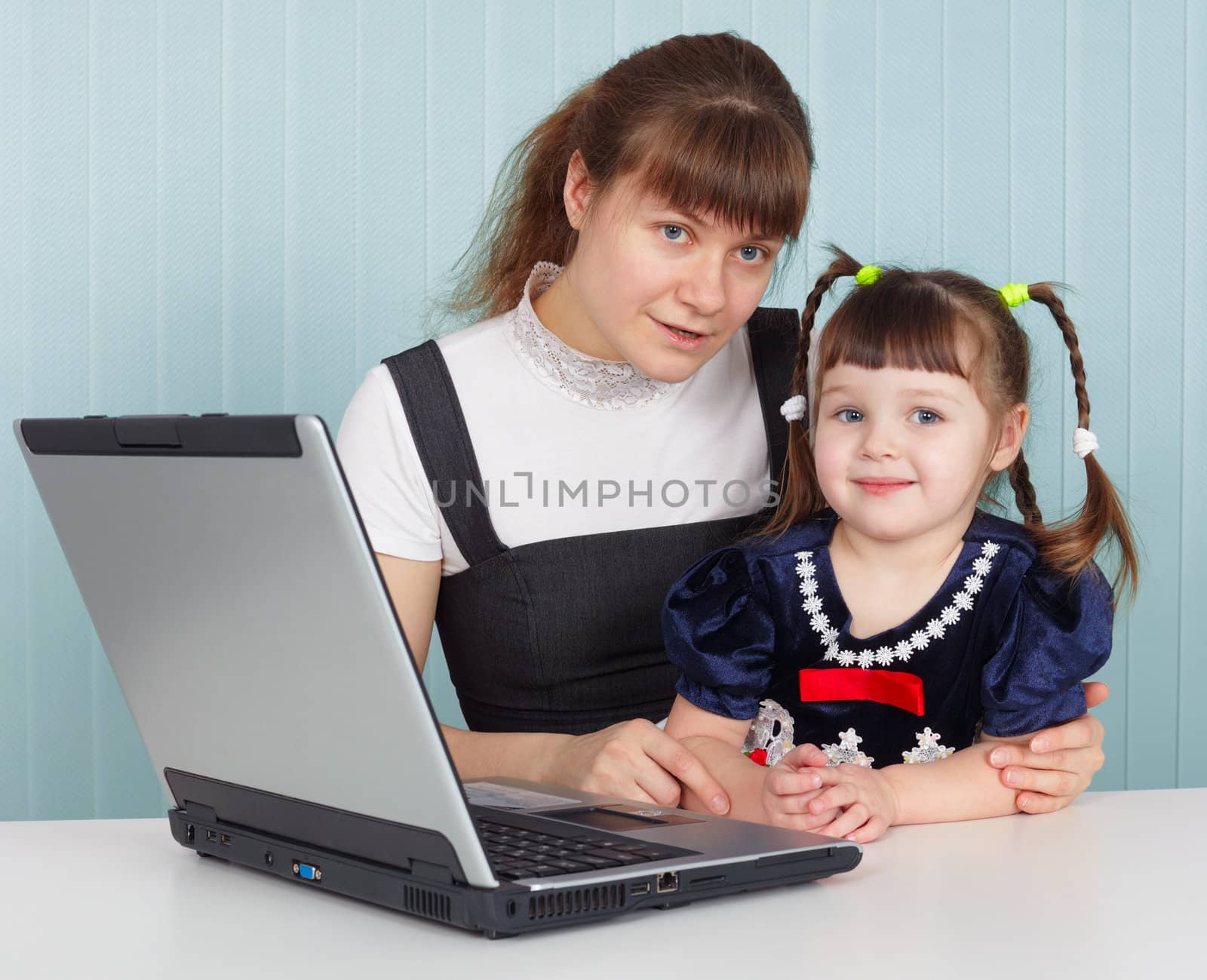 Mother and daughter sitting at table with a computer